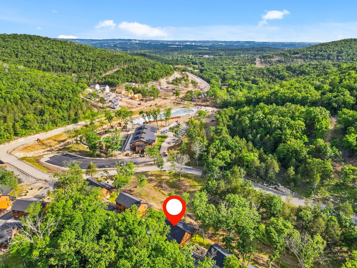A scenic overview of the property with lush green trees, rolling hills, a swimming pool area, winding roads, and spaces perfect for family gatherings and outdoor adventures. The layout reflects the active, family-friendly nature of the destination.