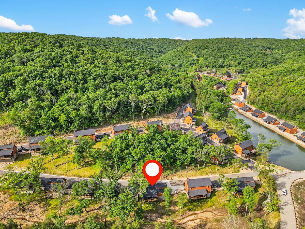 An exterior view highlighting a cluster of cabins nestled among lush greenery, with a winding road and a serene river nearby. The tranquil setting is complemented by hints of wildlife and the soft glow of sunset reflecting on the water, suggesting peaceful moments after a day of exploring.