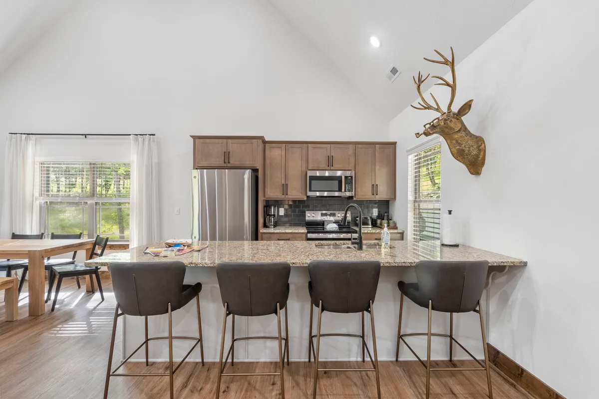 This image spotlights a modern kitchen with granite countertops, sleek appliances, and a wooden dining table. Subtle antler decor adds a touch of contemporary lodge style, and the scene suggests warmth, cleanliness, and readiness for shared meals and gatherings.